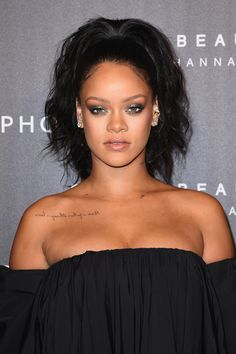 a close up of a person wearing a black dress with tattoos on her chest and shoulder