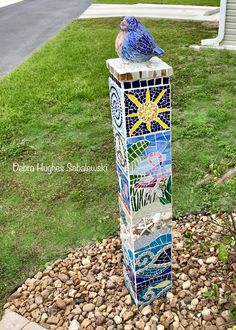 a blue bird sitting on top of a mosaic pole