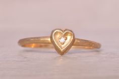 The Fifty: Natural Diamond Heart Ring in Yellow Gold. This simple ring centers on a round-cut natural diamond, beautifully set within a concave heart shape crafted in yellow gold. Currently sized at 5.25, the ring can be adjusted to fit any finger size for an additional fee upon request, ensuring a perfect fit. Love this piece, but don't have the money to spend right now? We offer FREE layaway on every item in our shop. With just 20% down, take one full year (interest-free) to pay off your new j Valentine's Day Yellow Gold Solitaire Diamond Ring, Heart-shaped Single Diamond Fine Jewelry Ring, 14k Gold Heart-shaped Solitaire Ring, Heart Ring In Yellow Gold With Single Diamond, Yellow Gold Heart Ring With Single Diamond, Yellow Gold Solitaire Heart Ring, Yellow Gold Solitaire Heart Ring With Round Cut, Anniversary Heart Cut Diamond Heart Ring, Yellow Gold Solitaire Heart Ring For Valentine's Day