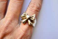 a woman's hand with a gold bow ring on it