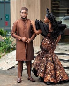 two people standing next to each other in front of a building and one is wearing a brown dress