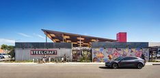 a car is parked in front of a steelcraft building with graffiti on the walls