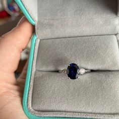 a woman's hand holding an engagement ring with a blue stone