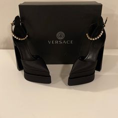 Versace Black Medusa Aevitas Platform Heels. Versace Satin Platform Pumps With Medusa Charm At Pin-Buckle Ankle Strap. Crystal-Cut Detailing At Ankle Strap That Is Adjustable. Silk-Blend Satin Heels In Black. Dust Bag Included. Brand New In Box. Size 40 Color: Black Pointed Toe Logo Embossed At Goatskin Footbed Covered Block Heel Covered Platform Midsole Medusa Hardware At Polished Calfskin Outsole Platform: H2.5 In Heel: H6.25 In Upper: Silk/Satin Sole: Leather Made In Italy. Medusa Heels Versace, Versace Heels Aesthetic, Luxury Closed Toe Platform Heels, Luxury Platform Heels With Closed Toe, Luxury Ankle Strap Heels For Night Out, Luxury Heels With Padded Heel For Party, Luxury Platform Heels For Party, Luxury Heels With Wrapped Heel For Gala, Shoe Inspo Heels