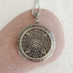 "Timeless and classic, this lovely, embossed antiqued silver locket will become a special addition to your jewelry collection. The locket is extra large at 46mm in diameter and opens for a secret place to keep pictures, messages, or whatever you like. The inside of this locket is deep and can hold two photos. The inside space is approximately 30mm in diameter. The locket is made from lightweight silver plated brass. It has been deeply embossed with an intricate pattern. It hangs on an antique si Engraved Locket Necklace With Round Pendant, Intricate Medallion Locket Necklace For Anniversary, Intricate Round Pendant Locket Necklace For Anniversary, Round Locket Necklace With Intricate Design, Antique Silver Round Locket Necklace For Anniversary, Ornate Round Pendant Locket Necklace For Anniversary, Classic Round Locket Necklace With Intricate Design, Anniversary Locket Necklace With Intricate Design, Vintage Style Engraved Round Pendant Locket Necklace