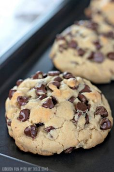 two chocolate chip cookies sitting on top of a cookie sheet