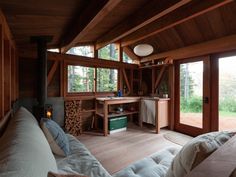 a living room filled with lots of furniture next to a fire place in the middle of a forest