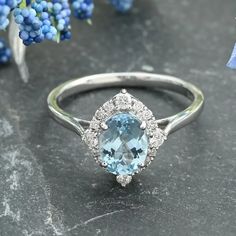 an oval blue topaz ring with diamond accents on a table next to some flowers