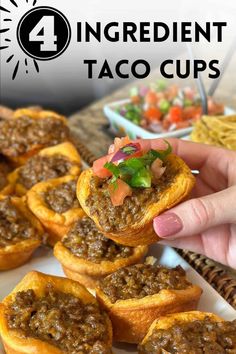 someone is holding up some taco cups on a white plate with other food in the background