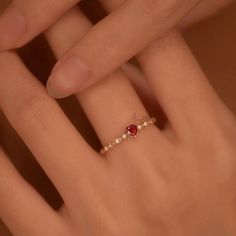 a woman's hand with a diamond and ruby ring on her finger, close up