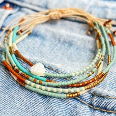 Dainty Turquoise & Brown Miyuki Delica Beaded String Bracelet Stack of 5, Adjustable & Minimalist & Boho Materials used: Original Miyuki Delica glass beads, mother-of-pearl heart, high quality parachute rope Adjustable Turquoise Wrap Bracelet With Tiny Beads, Turquoise Hippie Beaded Bracelets For Jewelry Making, Bohemian Friendship Bracelets With Tiny Heishi Beads, Bohemian Wrap Bracelet With Heishi Beads, Bohemian Resizable Heishi Beads Bracelets, Bohemian Friendship Bracelets With Tiny Round Beads, Bohemian Resizable Beads For Festivals, Resizable Bohemian Beads For Festivals, Hand-strung Turquoise Bohemian Friendship Bracelets