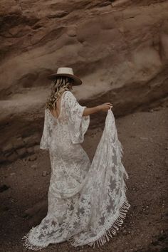 a woman in a white dress and hat is standing on the ground with her back to the camera