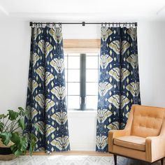 a living room with a chair, window and potted plant in front of it