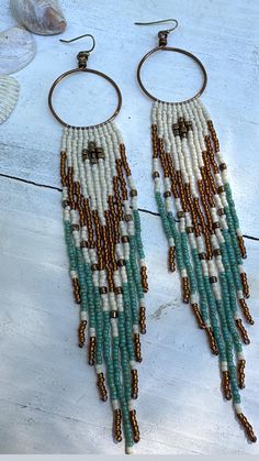 S o o r a j   earrings were handcrafted using colors matte cream, gold luster, Picasso turquoise and bronze with high quality Japanese seed beads. Suspended from hand crafted  antique brass hoops using quality Japanese nylon thread for durability. These come with silicone encapsulated antique brass backs to secure your earrings. Nickel and lead free. *LAST PICTURE IS FOR SIZE REFERENCE ONLY * Fringes swing beautifully and are light weight.  **Please care for your jewelry as you would with any va White Tassel Jewelry For Festival, White Bohemian Fringe Earrings, Festival White Jewelry With Tassels, Festival White Tassel Jewelry, Bohemian Gold Tassel Earrings With Round Beads, Handmade White Bohemian Tassel Earrings, White Bohemian Dangle Hoop Earrings, Gold Bohemian Tassel Earrings, Bohemian White Chandelier Earrings For Festivals