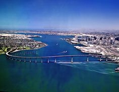 an aerial view of a bridge spanning the width of a large body of water in front of a city