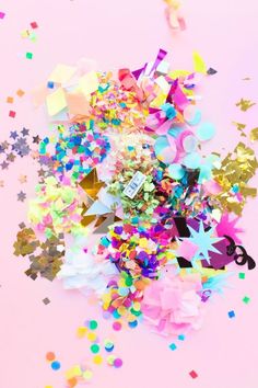 colorful confetti and streamers are scattered on a light pink background with stars