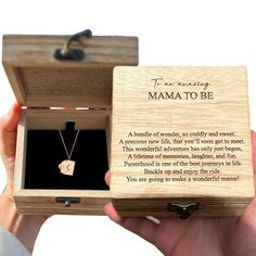 a person holding a wooden box with a necklace in it that says, the best thing mama to be