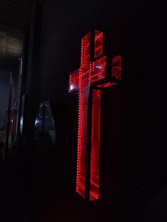 a red lighted cross hanging from the side of a wall