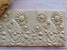 a cookie that has been decorated with flowers and gnomes on the side, next to a rolling pin