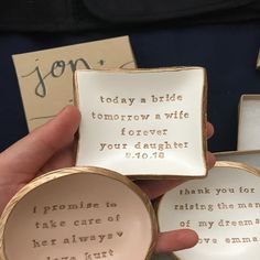 two small plates with words on them in gold and white, one being held by a woman's hand