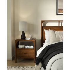 a bedroom with a bed, night stand and lamp on the side table next to it