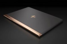 the back side of an hp laptop on a black surface with gold trimmings