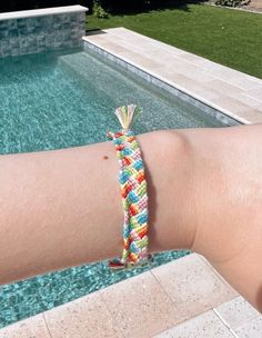 a person wearing a colorful bracelet next to a swimming pool