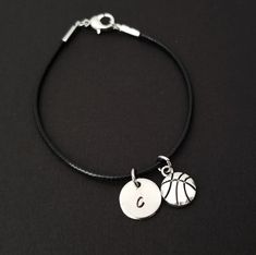 a black cord bracelet with a silver basketball charm