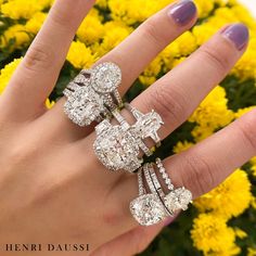 a woman's hand with three rings on it and yellow flowers in the background