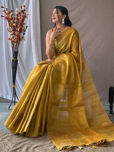 Add a touch of elegance and sophistication to your ethnic wardrobe with our beautiful mustard yellow zari weaving tissue silk traditional saree. This stunning saree is the perfect choice for all your upcoming festivities, weddings, and special occasions, adding a pop of vibrant color to your look.
Crafted from luxurious tissue silk fabric, this saree features intricate zari weaving work that adds a touch of traditional charm. The rich pallu with attached tassels enhances the overall appeal of th Gold Tussar Silk Pre-draped Saree With Pallu, Gold Tussar Silk Pre-draped Saree With Zari Weaving, Gold Bollywood Style Pre-draped Cotton Silk Saree, Festive Gold Pre-draped Saree With Zari Weaving, Gold Pre-draped Saree With Unstitched Blouse For Puja, Gold Katan Silk Pre-draped Saree For Eid, Gold Handloom Pre-draped Saree For Wedding, Gold Cotton Silk Pre-draped Saree With Dupatta, Gold Pre-draped Cotton Silk Saree With Dupatta