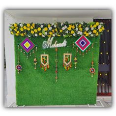 an artificial grass wall decorated with flowers and jewelry hanging from it's sides in front of a building