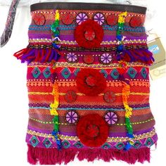 a multicolored bag with tassels and flowers on it's side