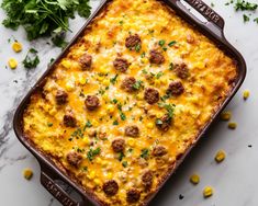 a casserole dish with meatballs, corn and parsley on the side