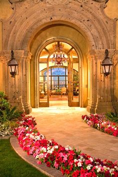 an entrance to a mansion with flowers in the foreground and chandelier above