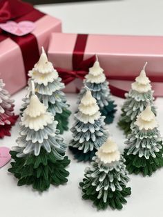 small christmas trees sitting next to a pink gift box