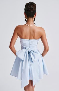 the back of a woman wearing a short blue dress with a bow at the waist