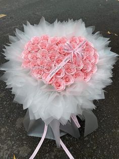 a bouquet of pink roses in the shape of a heart on top of a gray box