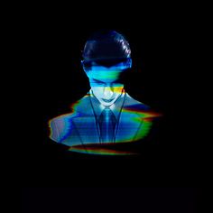 a man in a suit and tie is projected on a black background with multicolored lines