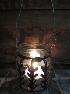 a glass jar with a candle inside sitting on a wooden table next to a wall