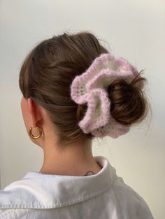 a woman is wearing a pink and white crochet hair scrunch