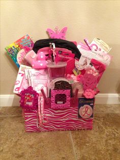 a pink and white basket filled with lots of stuff on the floor next to a wall