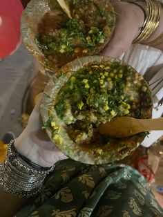 a person holding two plates with food in them and spoons next to each other