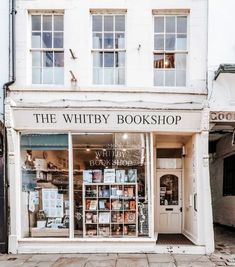 a store front with many books on display in it's glass windows and the words, the whitby book shop