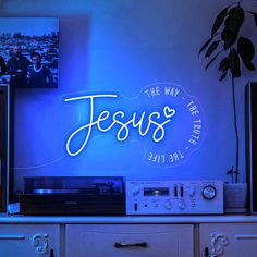 there is a blue neon sign that says jesus on the wall next to a radio