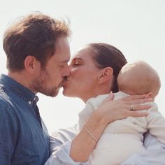 a man and woman kissing each other while holding a baby