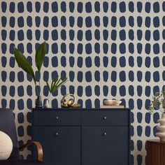 a living room with blue and white wallpaper, a black chair and two vases