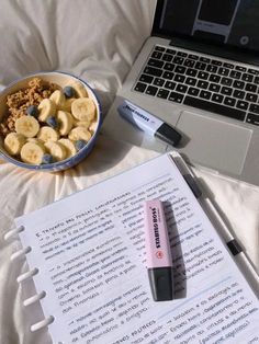 a bowl of bananas and cereal next to an open book with a pen on it