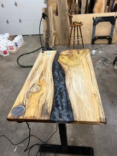 a table made out of wood with a black and white stripe on the edge, sitting in a workshop