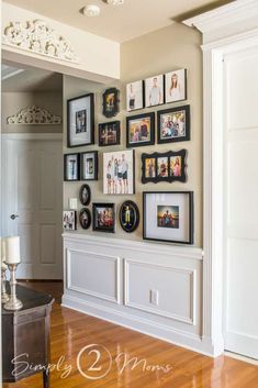 a wall filled with pictures and frames on top of a hard wood floor next to a white door