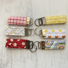 four key fobs are lined up on a white surface with flowers and hearts